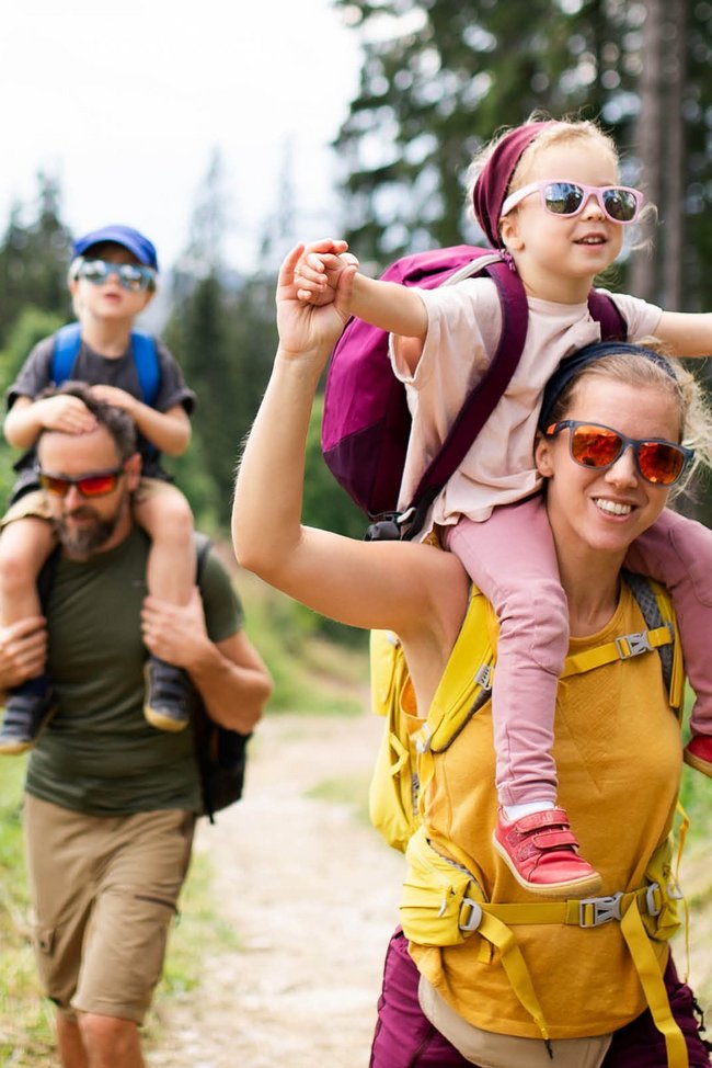 Eine Familie wandert auf einem Pfad durch den Wald.